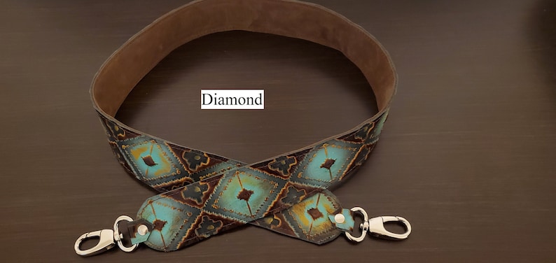 May include: A decorative leather strap with a diamond pattern in turquoise, brown, and gold. The strap has silver-coloured metal clasps on each end and a soft brown suede backing. The word "Diamond" is printed on the strap.