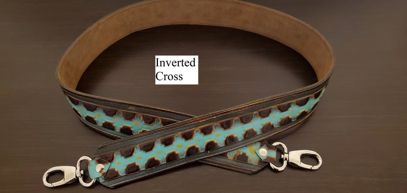 May include: A brown and turquoise leather bag strap with silver clasps. The strap has a repeating pattern of turquoise and brown shapes. The text "Inverted Cross" is visible on the image.