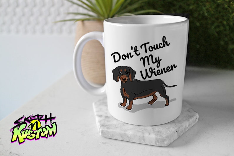 May include: White ceramic mug with a black and brown dachshund illustration and the text "Don't Touch My Wiener".
