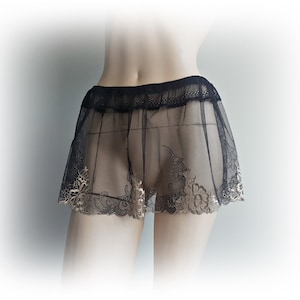 May include: Black sheer skirt with a gold floral lace trim. The skirt is made of a delicate, lightweight fabric and has an elastic waistband.