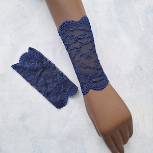May include: A pair of blue lace wrist cuffs. The cuffs are made of delicate lace with a floral pattern.