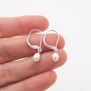 May include: A pair of silver dangle earrings with small white pearl drops.