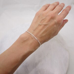 K&ouml;nnte beinhalten: Ein zartes Armband mit Silber-Kordelkette. Das Armband wird am Handgelenk einer Person pr&auml;sentiert und zeigt seine feinen Glieder und seinen subtilen Glanz. Ein schlichtes, aber elegantes Schmuckst&uuml;ck.