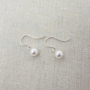 May include: A pair of silver dangle earrings with white pearl accents.