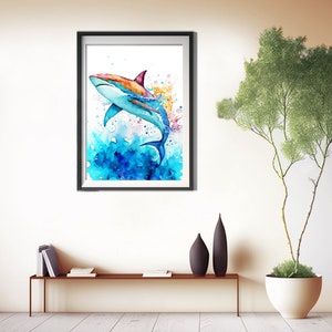 Puede incluir: Una pintura de acuarela de un tibur&oacute;n colorido saltando fuera del agua. El tibur&oacute;n es azul, naranja y blanco. El agua es azul y verde con salpicaduras blancas.
