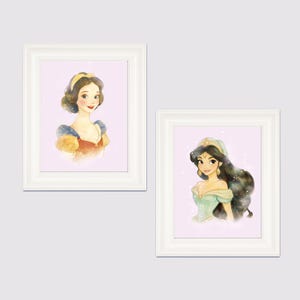 May include: Two framed watercolor prints featuring portraits of animated princesses. One print shows a princess with dark hair and a yellow headband, wearing a red and blue dress. The other print depicts a princess with long black hair and a green dress.