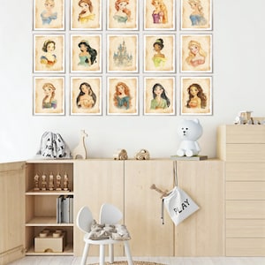 May include: A set of 15 framed prints featuring Disney princesses and the iconic Cinderella's castle. The prints are in a watercolor style and have a vintage aesthetic. The prints are arranged in a grid pattern on a white wall.
