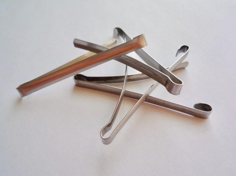 Op de afbeelding: Een set van vijf zilveren metalen haarclips. De clips zijn allemaal in verschillende maten en vormen en liggen op een witte ondergrond.