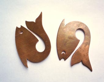 May include: Two copper fish-shaped metal charms. The fish on the left is facing right and has a tail that curls around to form a loop. The fish on the right is facing left and has a tail that curls around to form a loop.