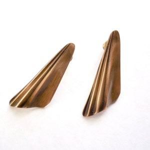 May include: A pair of gold-toned earrings with a geometric, fan-shaped design.