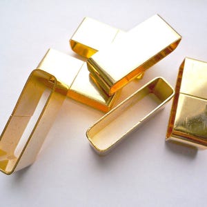 May include: Five gold-colored metal belt buckle closures. The buckles are rectangular and have a smooth, polished finish.
