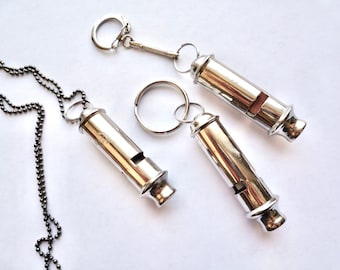 May include: Three silver whistles, one on a chain, one on a key ring, and one on a spring-loaded key chain.