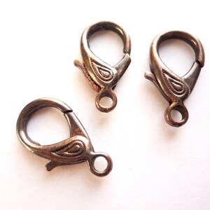 May include: Three silver-toned metal lobster clasps with a decorative paisley design. The clasps are used for jewelry making.