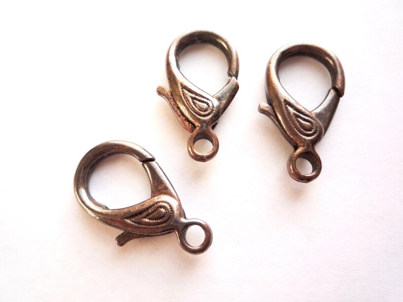 May include: Three silver-toned metal lobster clasps with a decorative paisley design. The clasps are used for jewelry making.