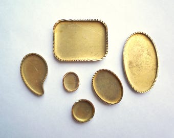 May include: Six gold-colored metal trays of various shapes and sizes. The trays have a decorative, textured edge.