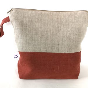 May include: A large zippered pouch made of linen fabric. The top half of the pouch is a light beige color, and the bottom half is a deep reddish-brown color.