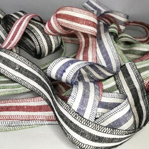 May include: A collection of striped fabric ribbon in various colors, including black, white, red, green, and blue. The ribbon is woven with a black and white stripe pattern and has a stitched edge.