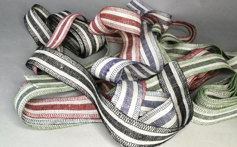 May include: A collection of striped fabric ribbon in various colors, including black, white, red, green, and blue. The ribbon is woven with a black and white stripe pattern and has a stitched edge.