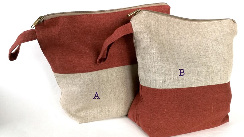 May include: Two linen zippered pouches, one red and beige, the other beige and red. The larger pouch has a handle and is labeled "A". The smaller pouch is labeled "B".
