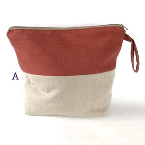 May include: A red and beige zippered pouch with a handle. The pouch is made of a linen fabric.