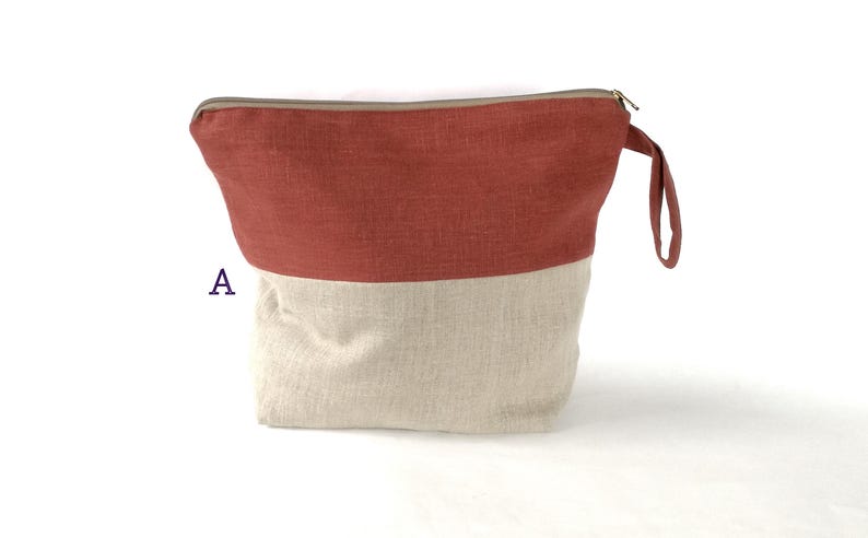 May include: A red and beige zippered pouch with a handle. The pouch is made of a linen fabric.