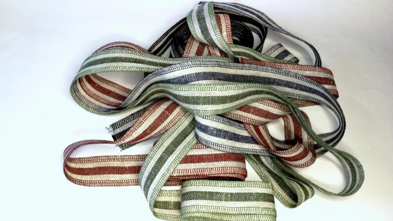 May include: A collection of striped ribbon in red, green, and blue colors. The ribbon is woven with a linen texture.
