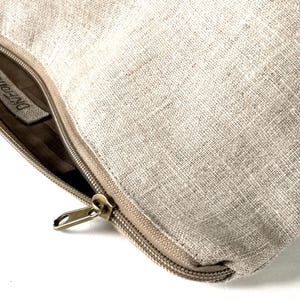 May include: A beige linen zippered pouch with a brown leather zipper pull and a label that reads "Dreamweaver".
