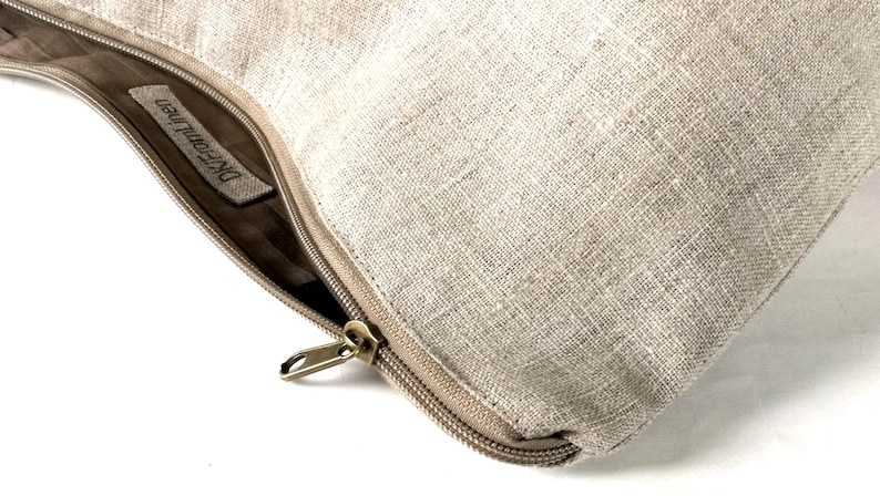 May include: A beige linen zippered pouch with a brown leather zipper pull and a label that reads "Dreamweaver".