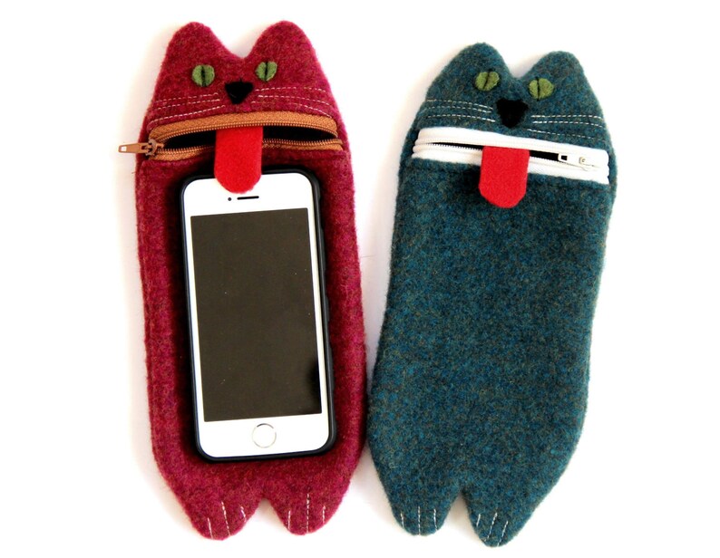 Puede incluir: Dos fundas para tel&eacute;fono de fieltro con forma de gato con la boca abierta y la lengua fuera. La funda de la izquierda es roja y la funda de la derecha es azul.