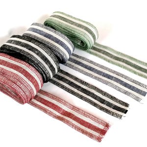 May include: Four rolls of striped fabric ribbon in red, black, blue, and green. The ribbon is woven with white stripes.