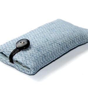 Puede incluir: Una funda para teléfono de tela azul y blanca con cierre de botón negro.