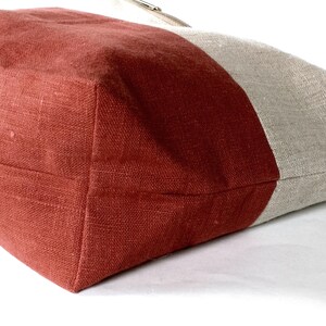 May include: A red and beige linen tote bag with a contrasting color block design. The bag is made of a soft, natural fabric and has a simple, understated style.