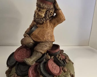 Könnte beinhalten: Detaillierte Figur eines sitzenden Gnom mit brauner Kleidung und einem rot umrandeten Hut, umgeben von Pokerchips. Die Basis ist ein Blatt mit Eicheln und dem Text "Chubby Clark 1986" und "Tom Clark" ist sichtbar.