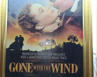 May include: A framed movie poster for "Gone With The Wind" featuring Clark Gable and Vivien Leigh. The poster has a gold frame and includes text such as "Presented in Technicolor Brilliance" and "In Specially Selected Theatres June 26."