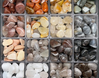 Puede incluir: Una colección de piedras pulidas de varios colores y texturas, dispuestas en una cuadrícula de 10 cuadrados. Las piedras incluyen tonos claros, blancos, grises, marrones y naranjas.