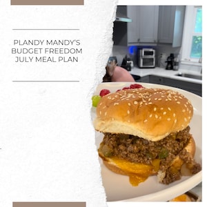 May include: A close-up of a cheeseburger with a sesame seed bun, ground beef, and melted cheese. The burger is on a white plate with a side of grapes and raspberries.
