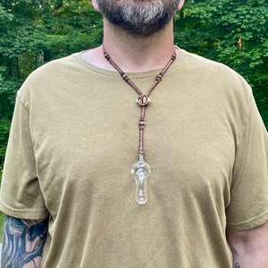 May include: A brown leather necklace with a glass pendant and a wooden charm with the letters "M.S.K." on it.