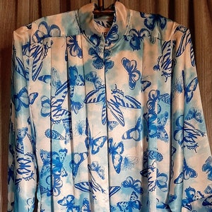May include: A white satin robe with a blue butterfly print. The robe has a mandarin collar and three-quarter sleeves.