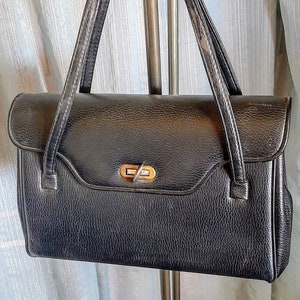 Double strap black leather handbag, clasp closure, bottom metal feet, 2 open pockets and a zipper pocket inside in excellent condition