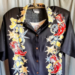 Puede incluir: Una camisa negra de manga corta con botones y un estampado de temática western. El estampado presenta botas de vaquero rojas, estrellas amarillas y diseños de cuerda azul.