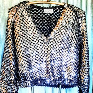 Maglione pullover nero a maniche lunghe con scollo a V, modello THREE FLAGGS California, decorato con paillettes argentate. È in condizioni eccellenti, ML