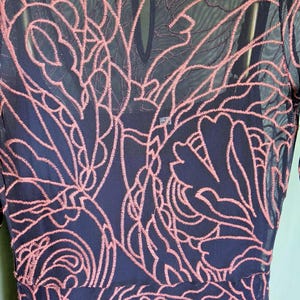 May include: Navy blue dress with pink floral embroidery. The dress has a round neckline and long sleeves. The brand tag "jade" is visible at the neckline.