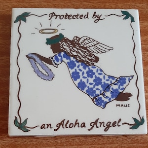 May include: A white ceramic tile with a brown border and a floral design. The tile features a cartoon angel with a halo, wings, and a lei. The text "Protected by an Aloha Angel" is written in brown lettering.