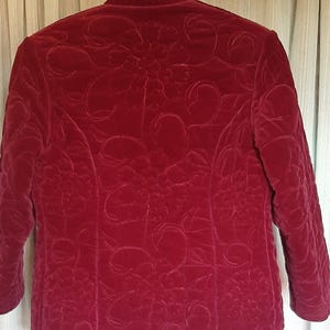 Puede incluir: Chaqueta acolchada burdeos con cuello mandar&iacute;n y mangas tres cuartos. La chaqueta presenta un intrincado estampado floral en toda la tela. El dise&ntilde;o acolchado a&ntilde;ade textura y dimensi&oacute;n a la prenda, creando un aspecto sofisticado.