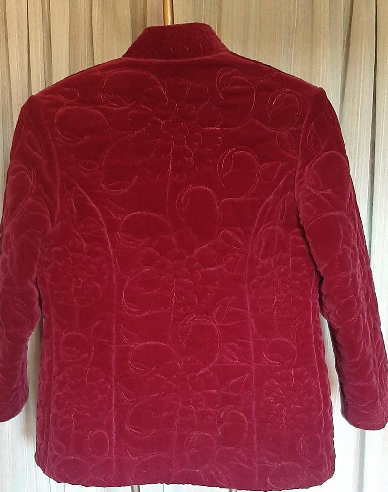 Puede incluir: Chaqueta acolchada burdeos con cuello mandar&iacute;n y mangas tres cuartos. La chaqueta presenta un intrincado estampado floral en toda la tela. El dise&ntilde;o acolchado a&ntilde;ade textura y dimensi&oacute;n a la prenda, creando un aspecto sofisticado.