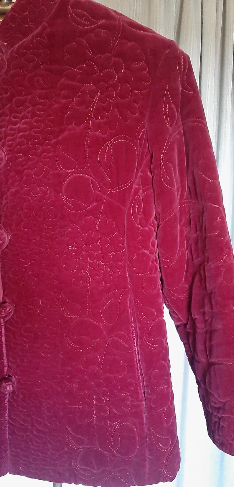 Puede incluir: Chaqueta de terciopelo burdeos con estampado floral. La chaqueta presenta un dise&ntilde;o acolchado con cierre de botones y mangas largas. El estampado floral est&aacute; cosido con hilo blanco.