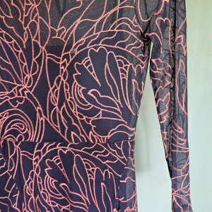 May include: A navy blue dress with a sheer overlay featuring a pink floral pattern. The dress has long sleeves and a round neckline. The brand name "jade" is visible on a tag near the neckline. The dress is a fit and flare style.