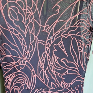 May include: A navy blue dress with a pink floral lace overlay. The dress has a round neckline and long sleeves. The brand label "jade" is visible at the neckline.