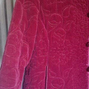 Puede incluir: Chaqueta de terciopelo acolchada burdeos con estampado floral. La chaqueta presenta cuello mandar&iacute;n, mangas largas y cierre de botones. El dise&ntilde;o floral est&aacute; cosido con un hilo m&aacute;s claro, creando un contraste sutil. La chaqueta tiene un bolsillo en el lado izquierdo.