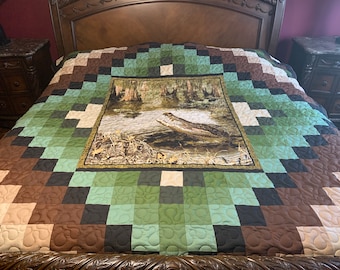 May include: A brown, green, and beige quilt with a square pattern. The center of the quilt features a close-up image of an alligator in a swamp.
